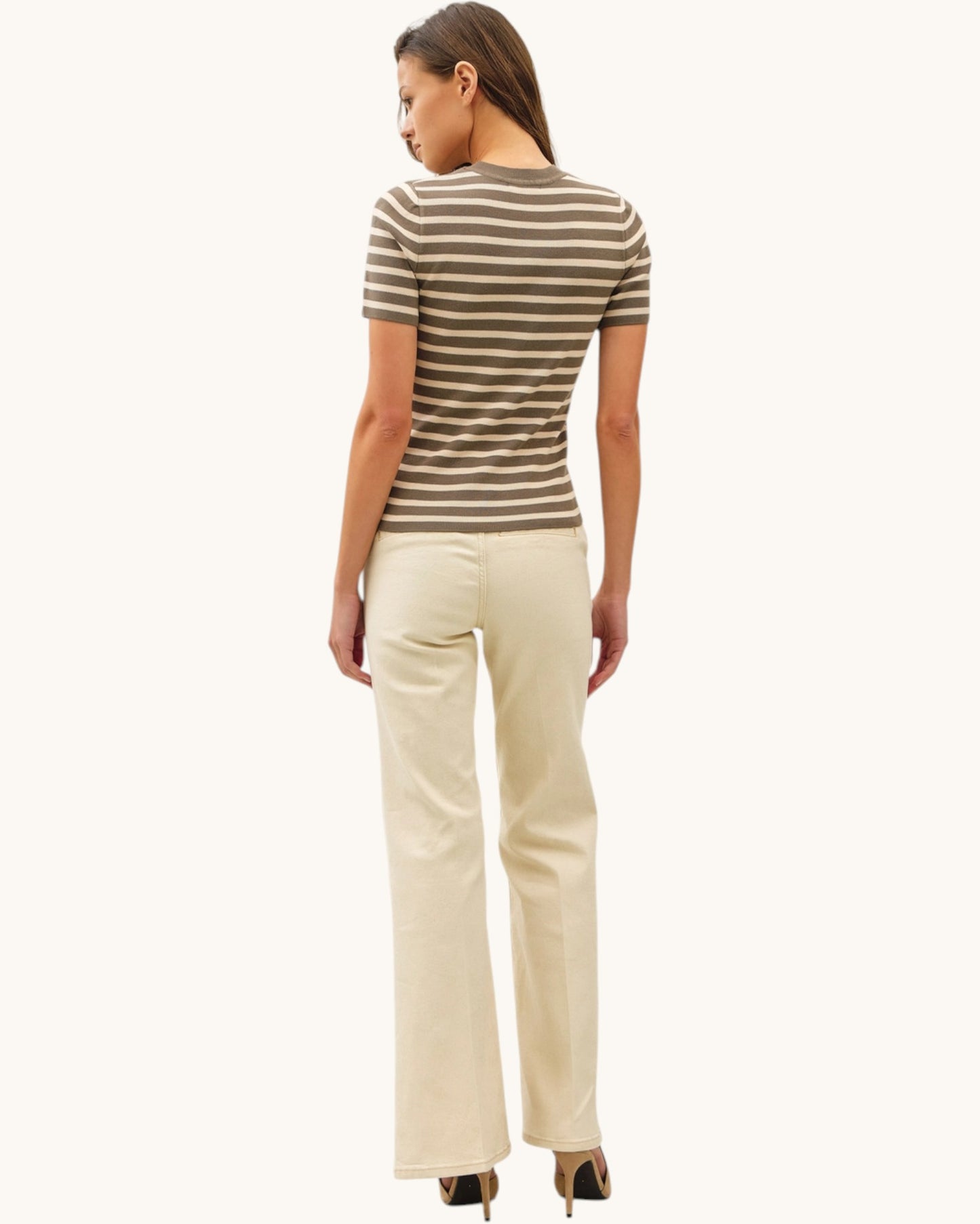 Woman wearing a striped short sleeve shirt and beige pants on a white background.