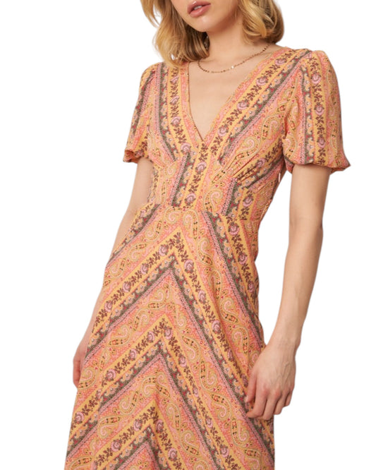 Woman wearing a soft pink paisley patterned midi dress on a white background.