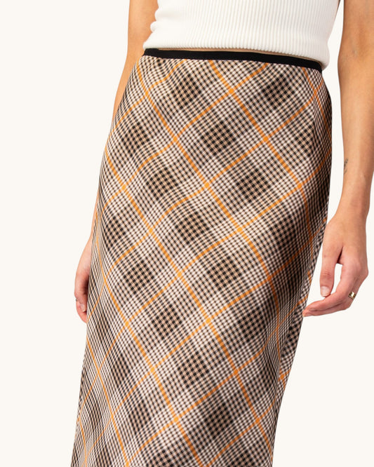 Close up of a brown, cream, and orange grid plaid midi pencil skirt front view.
