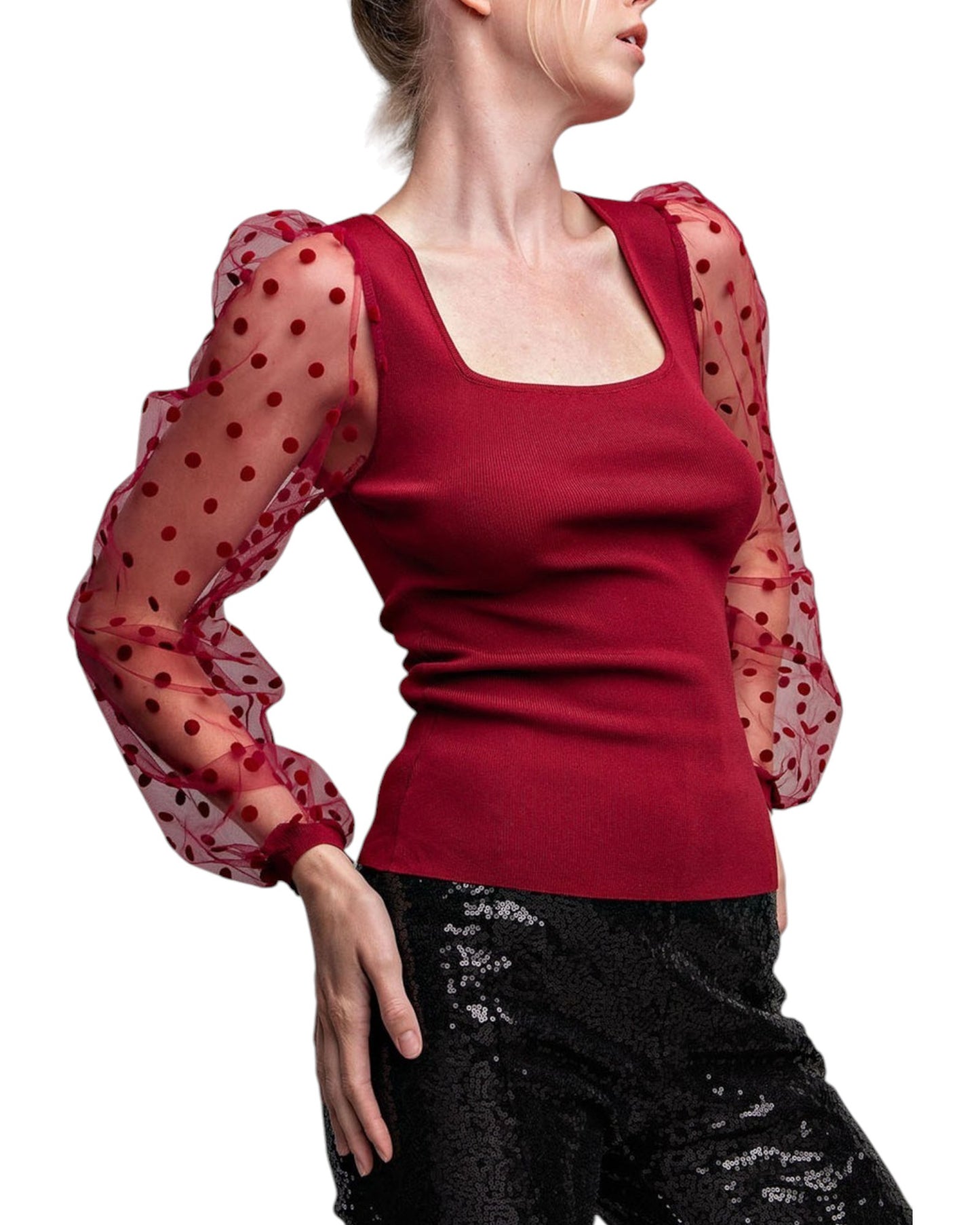 Woman wearing a merlot colored top with long, sheer sleeves with velvet polka dots.