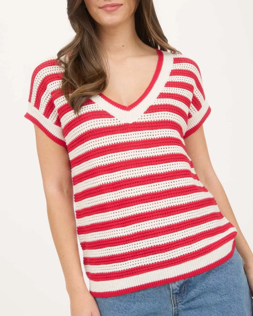 Woman wearing a red and white striped cotton short sleeve sweater with blue jeans on a white background.