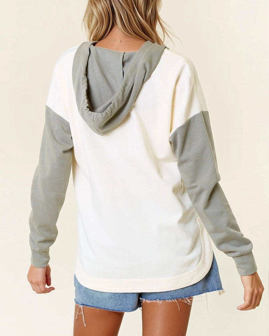 Woman wearing a Sage and Ivory Color Block Hoodie with curved hem and kangaroo pocket.