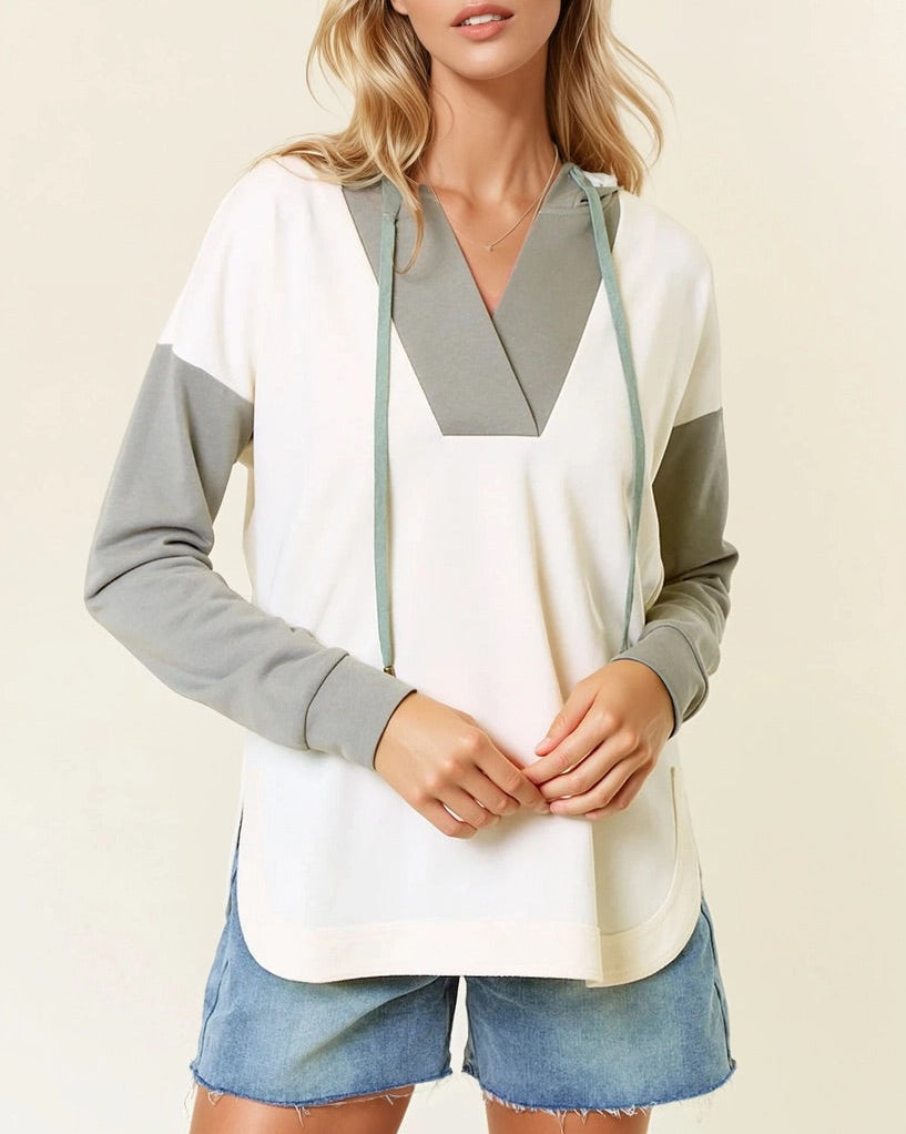 Woman wearing a Sage and Ivory Color Block Hoodie with curved hem and kangaroo pocket.