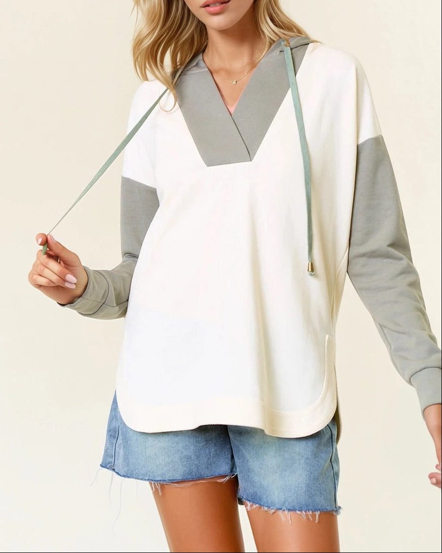 Woman wearing a Sage and Ivory Color Block Hoodie with curved hem and kangaroo pocket.