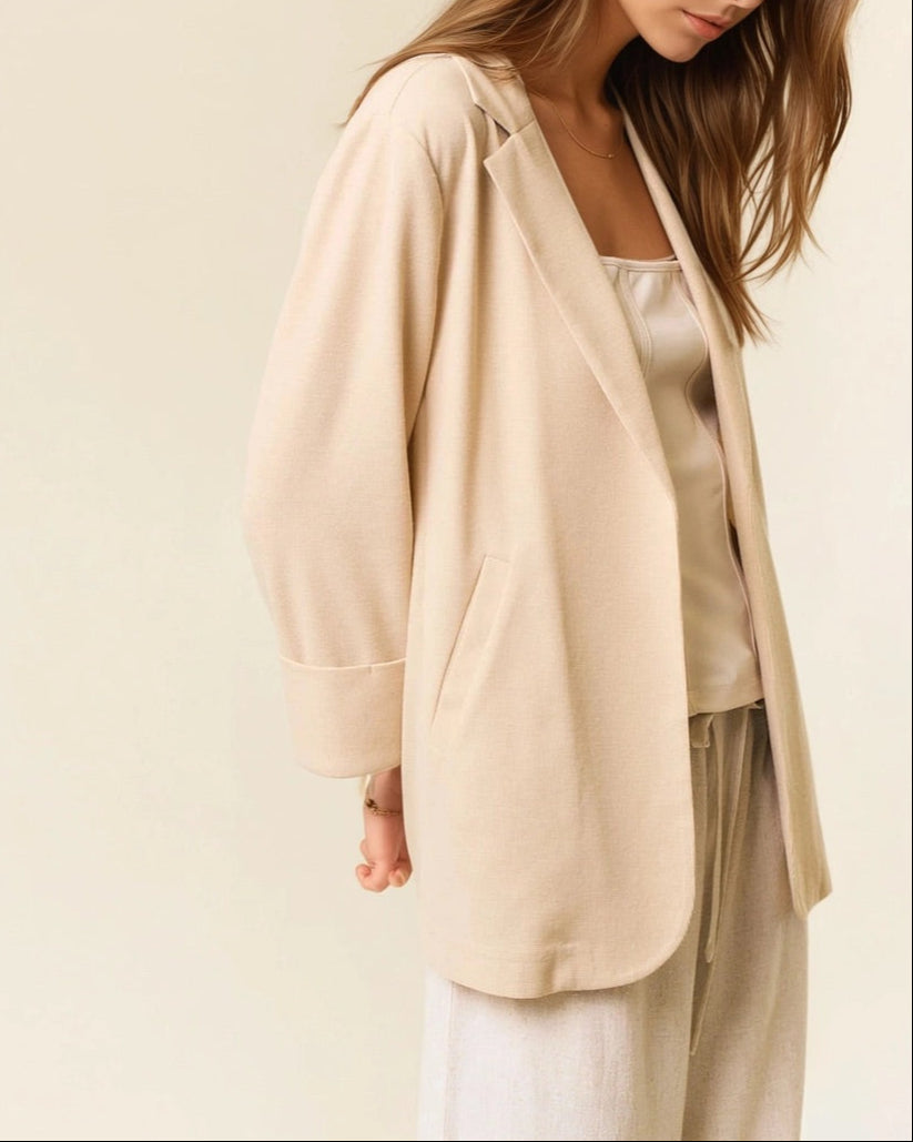 Woman wearing a beige cardigan over a white top and pants on a beige background
