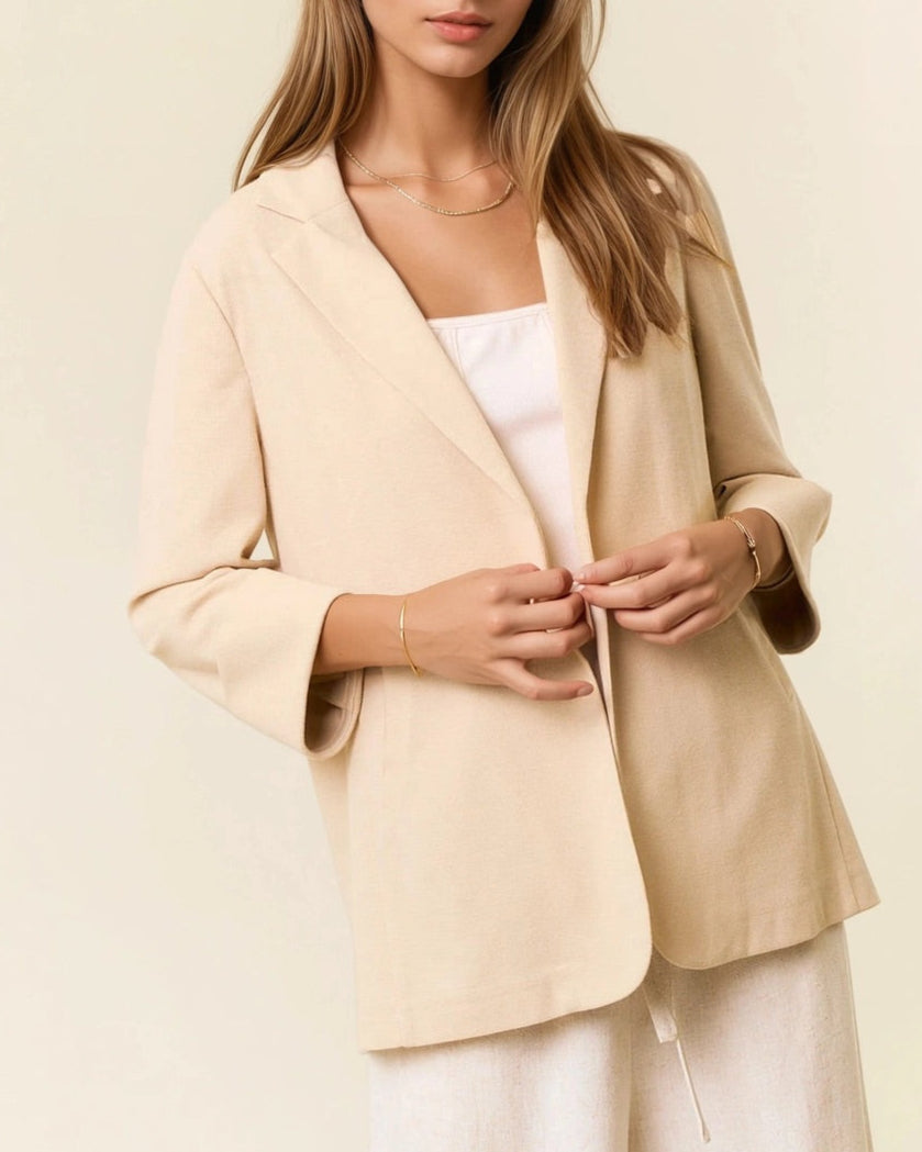 Woman wearing a beige blazer over a white top on a light background.