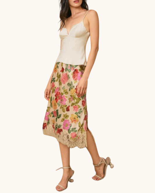 Woman wearing a floral skirt and cream top on a white background.
