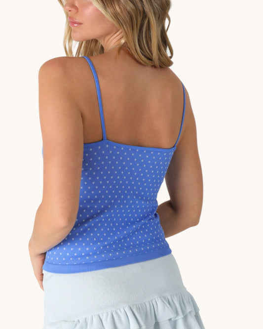 Woman wearing a blue polka dot tank top on a white background.
