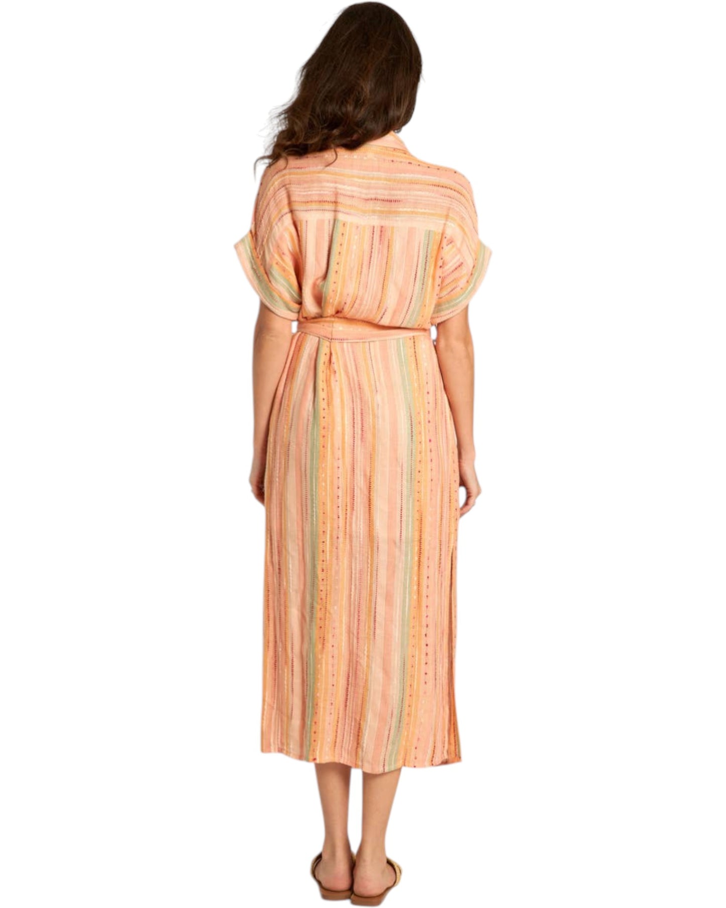 Woman wearing a peach-colored striped midi dress with a slit on a white background.