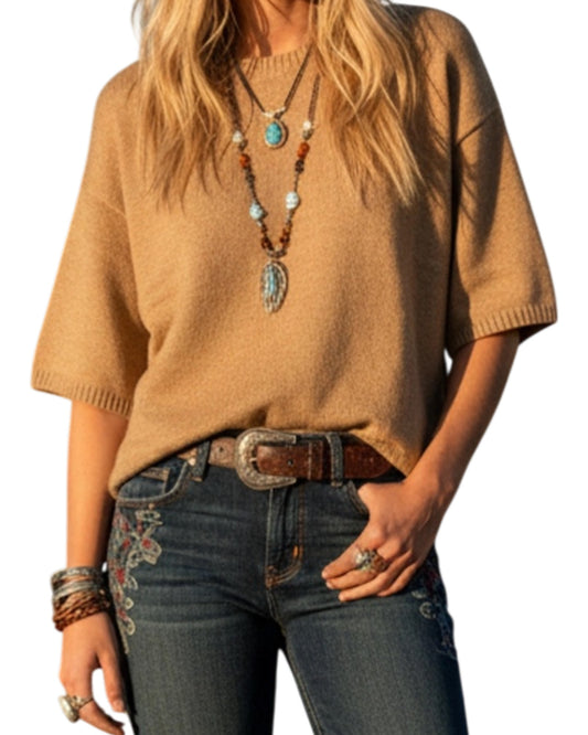 Person wearing a tan sweater and blue jeans with a belt, on a white background.