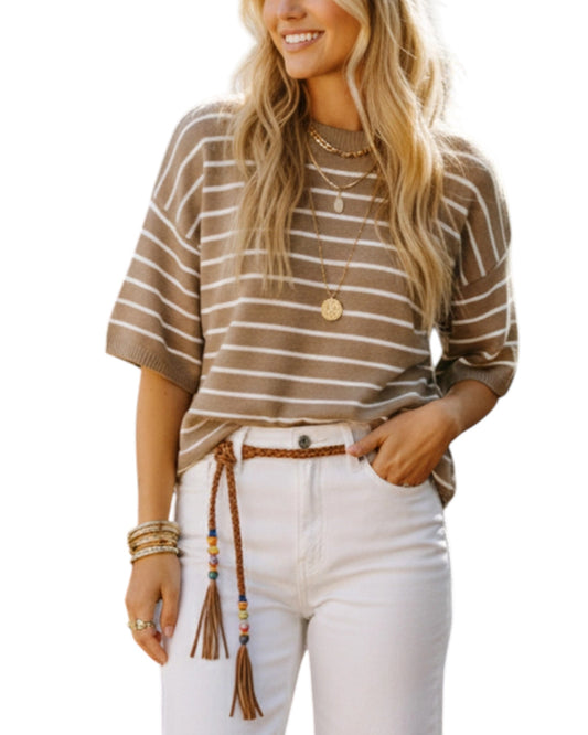 Woman wearing a striped shirt and white pants with a tassel belt on a white background.