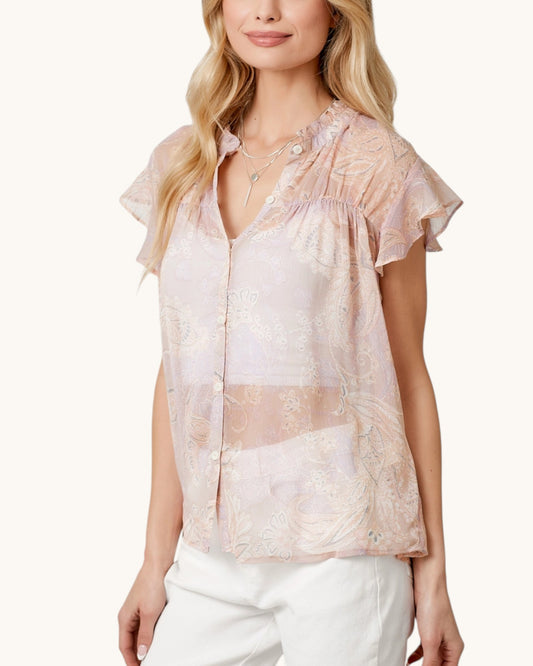 Woman wearing a sheer blush pink & paisley short sleeve button up with a white background.