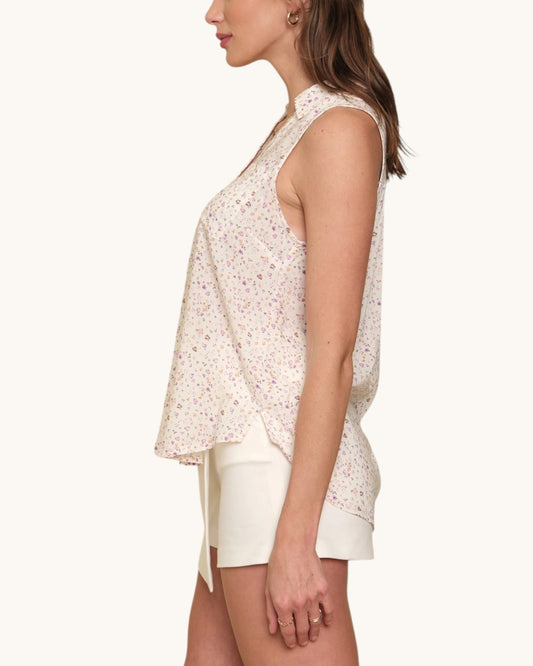 Woman wearing a semi-sheer sleeveless top with floral pattern on a white background.