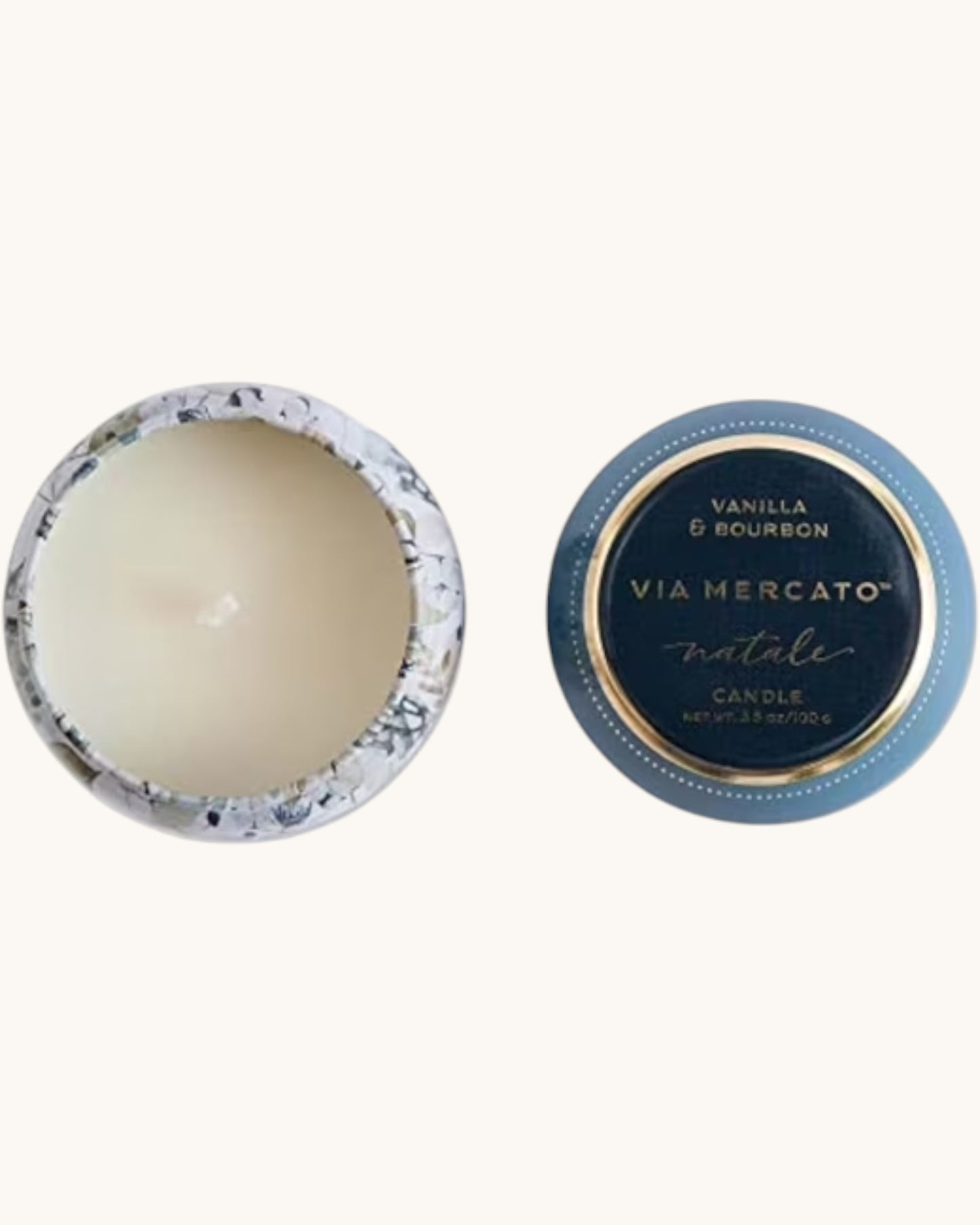 An open round candle tin showing cream-colored wax inside, alongside its matching blue and gold lid printed with 'VIA MERCATO natale' and 'VANILLA & BOURBON'.