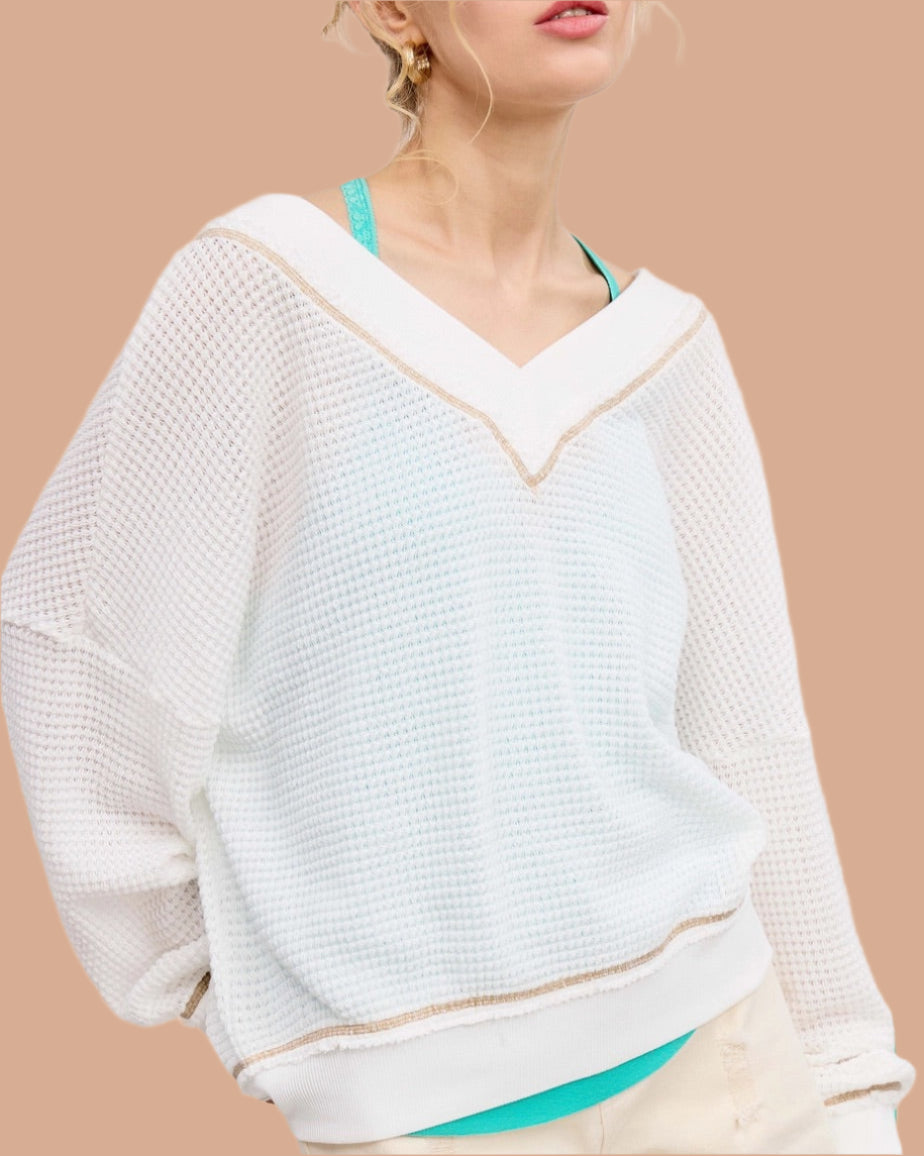 Woman wearing a white textured waffle knit long sleeve top.