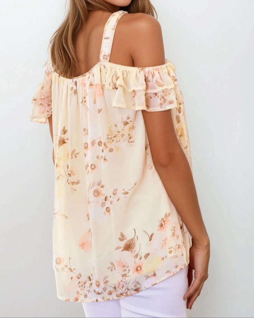 This image features the "Buttercream Blossom Off Shoulder Ruffle Top," a charming and trendy garment for spring. The top is adorned with a floral pattern on a light cream background, enhancing its delicate and feminine appeal.