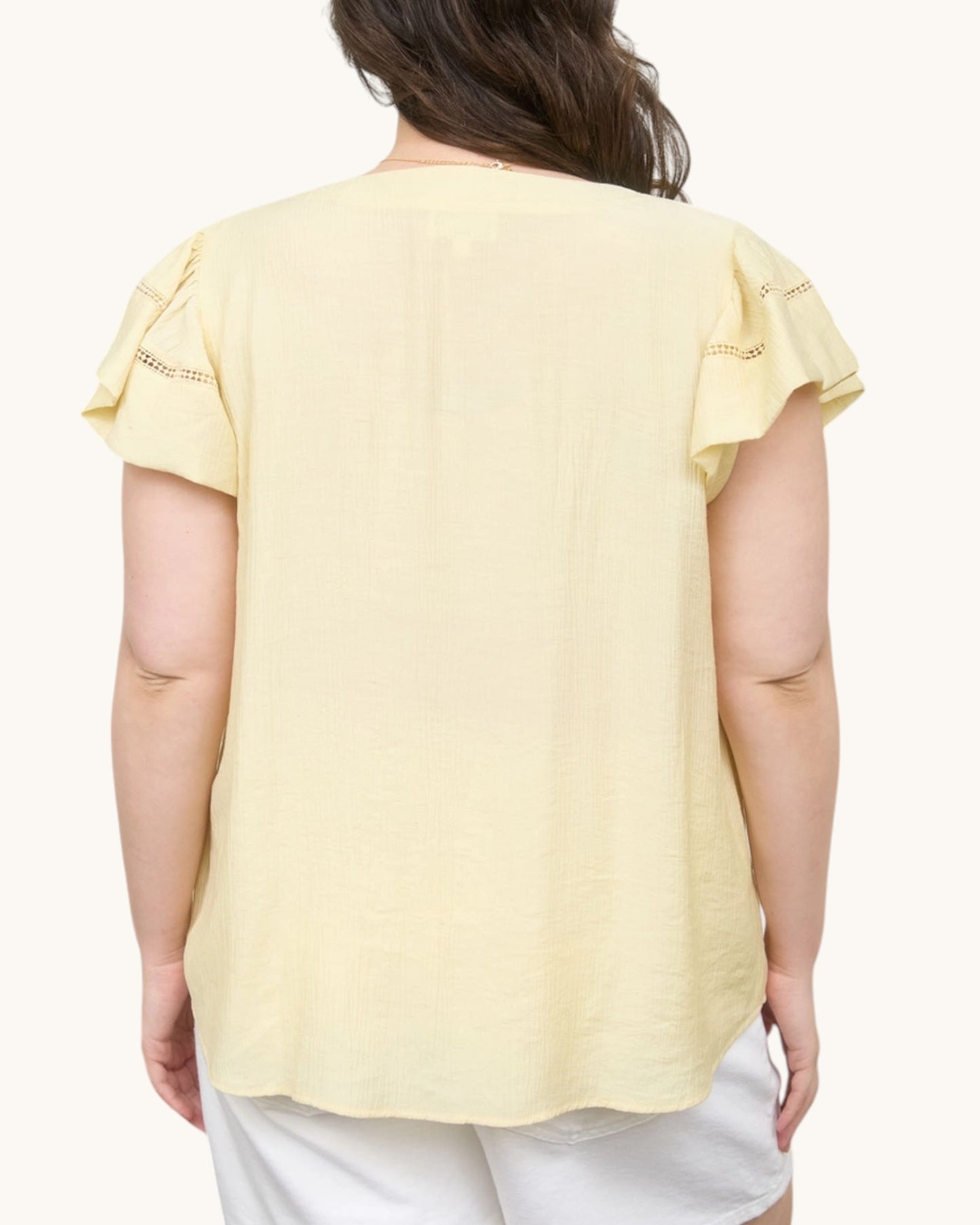 Back view of a pale yellow short sleeve top with ruffle sleeves.