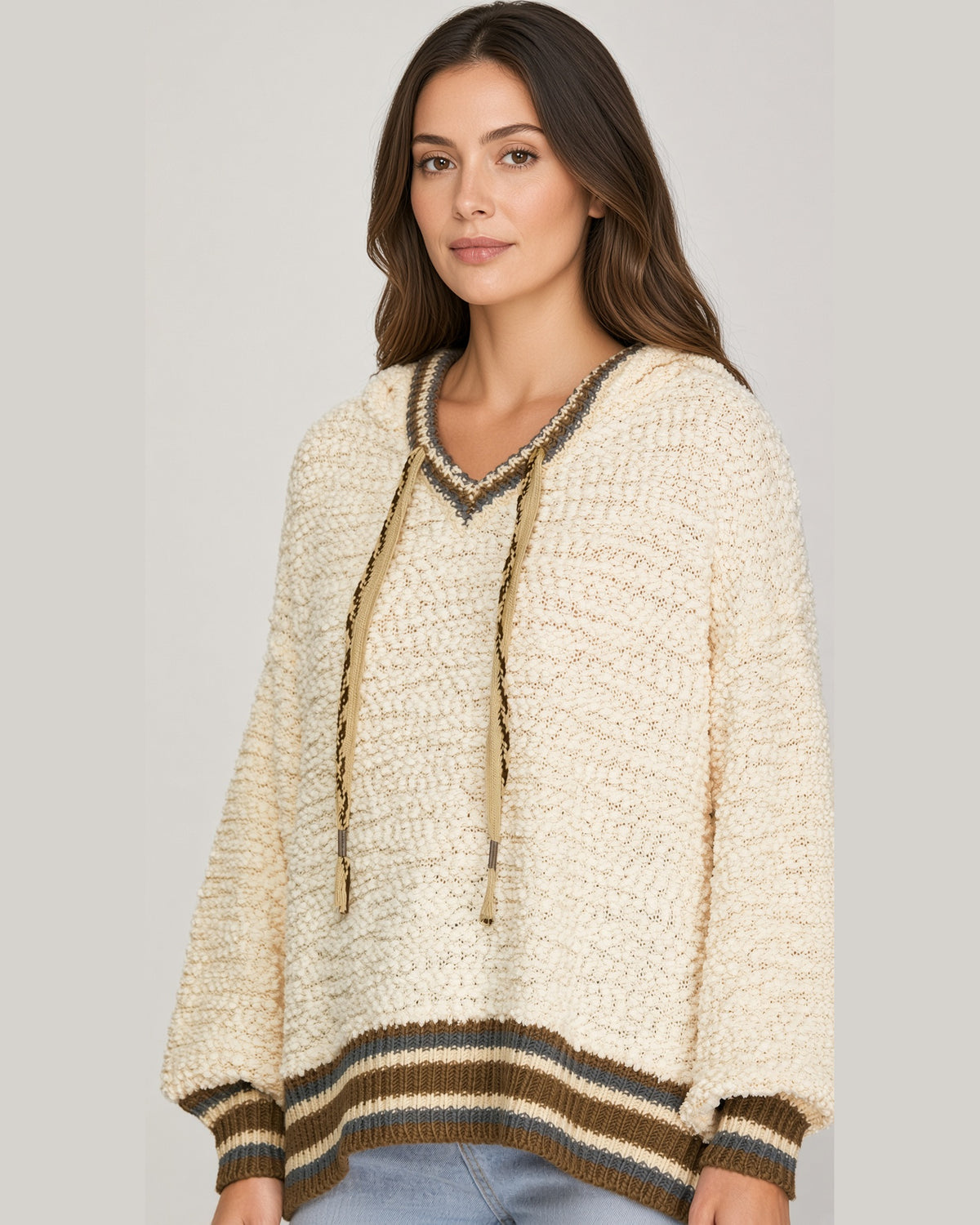 Front view of buttercream textured hoodie sweater with drawstrings and olive and brown striped cuffs and hem.