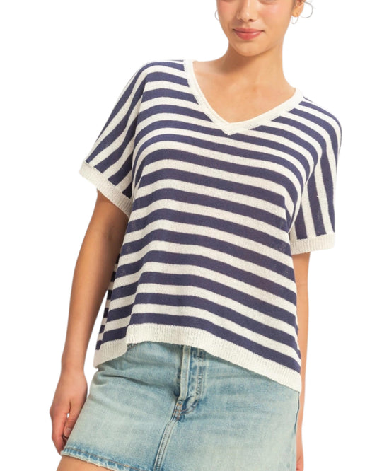 Woman wearing a blue and white striped shirt with denim shorts on a white background.