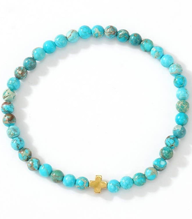 Turquoise beaded bracelet with a gold cross charm on a white background.