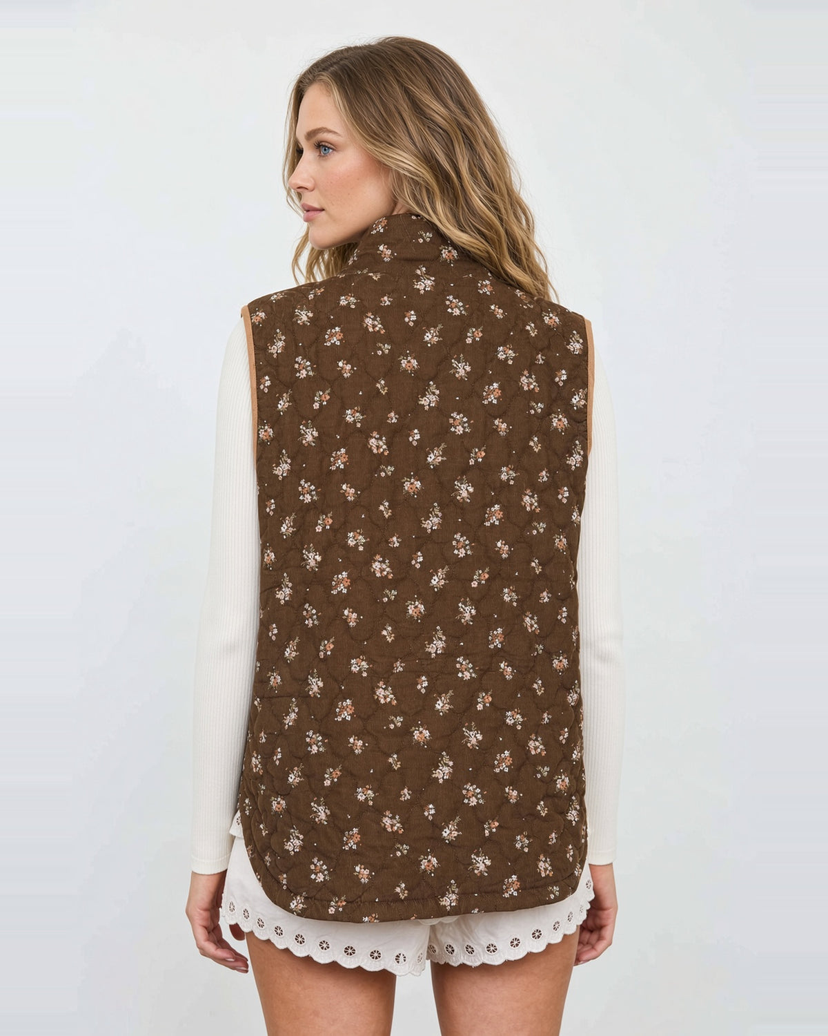 Back view of the Hazel Bloom quilted vest, showing small floral clusters across the brown shell.