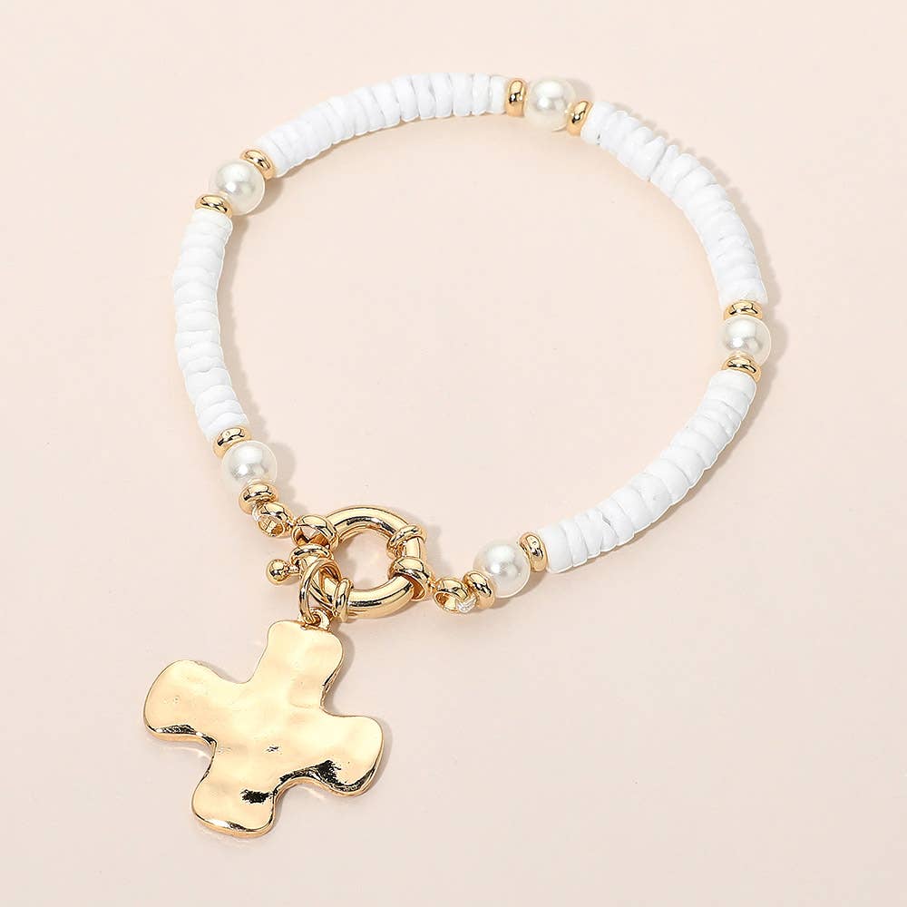 Bracelet with white beads and gold cross charm on a beige background