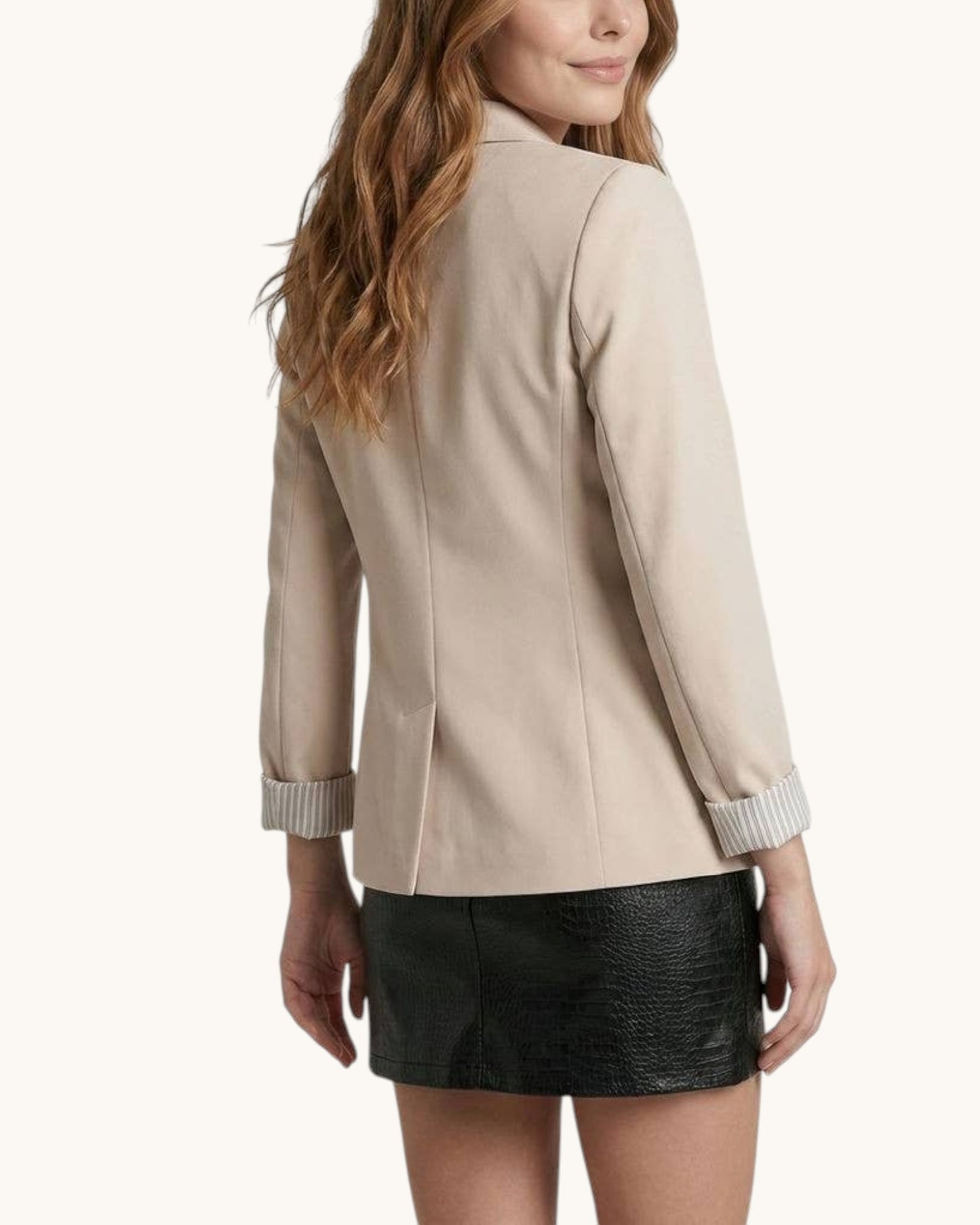 Back view of a woman wearing a beige jacket with striped cuffs on a white background.