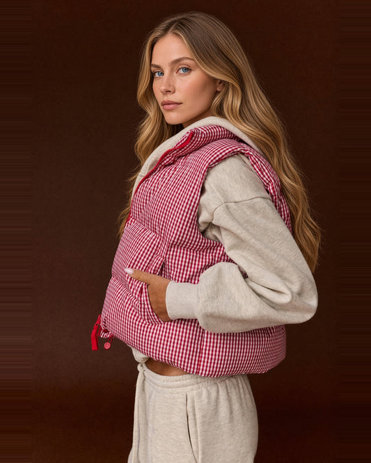 Side view of red and white gingham cropped puffer vest with horizontal quilting and model’s hand in the pocket.