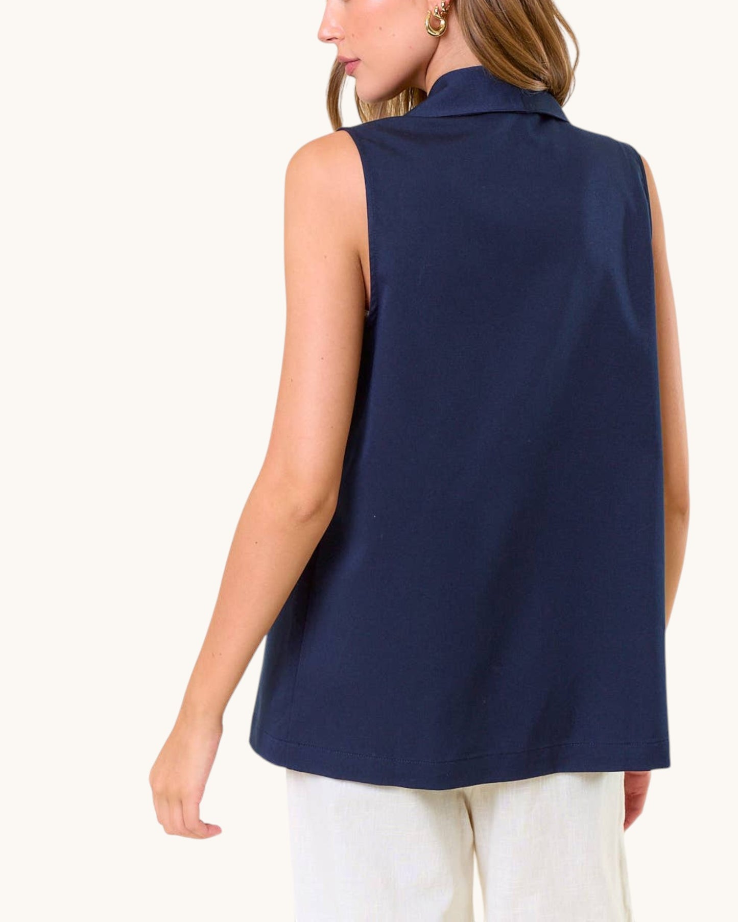 Back view of a woman wearing a navy sleeveless top on a white background.