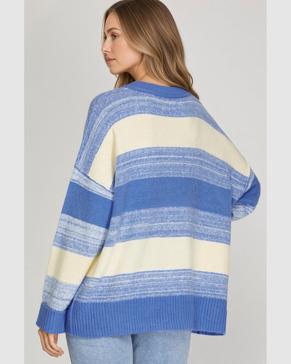 Back view of model wearing oversized blue and cream striped sweater.