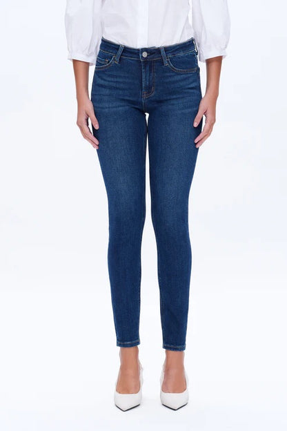 Model wearing dark blue mid-rise skinny jeans with a form-fitting silhouette and ankle-length cut.
