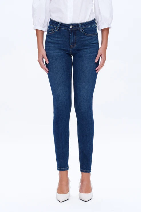 Model wearing dark blue mid-rise skinny jeans with a form-fitting silhouette and ankle-length cut.