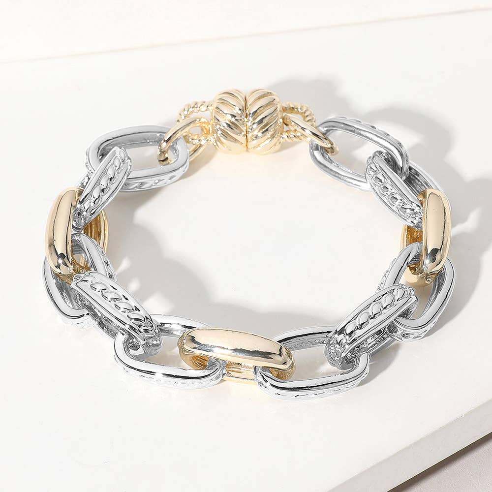 Gold and silver chunky link bracelet on a white surface. 