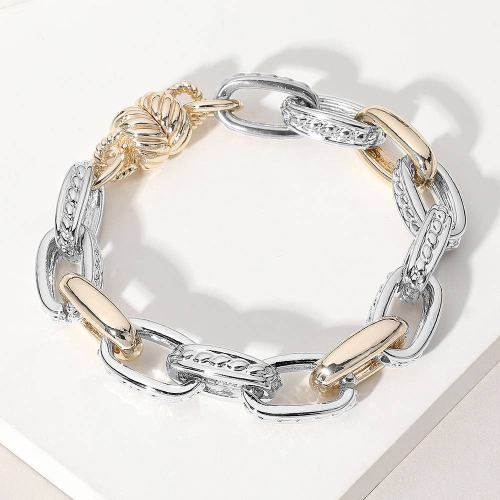 Bracelet with silver and gold links on a white surface.