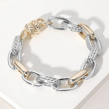 Bracelet with silver and gold links on a white surface.