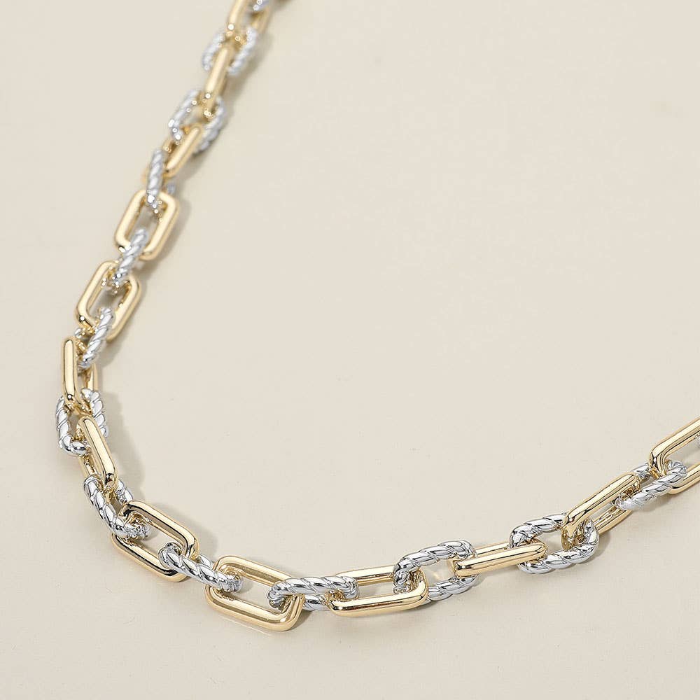 Two-tone gold and silver chain necklace on a beige background.