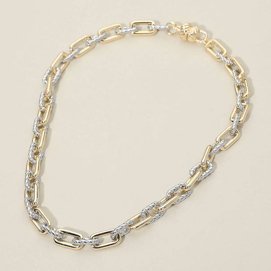 Gold and silver chain statement necklace on a beige background.