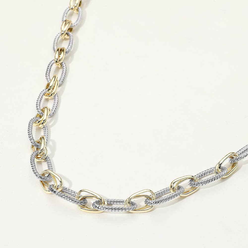Gold and silver chain necklace on a light background.