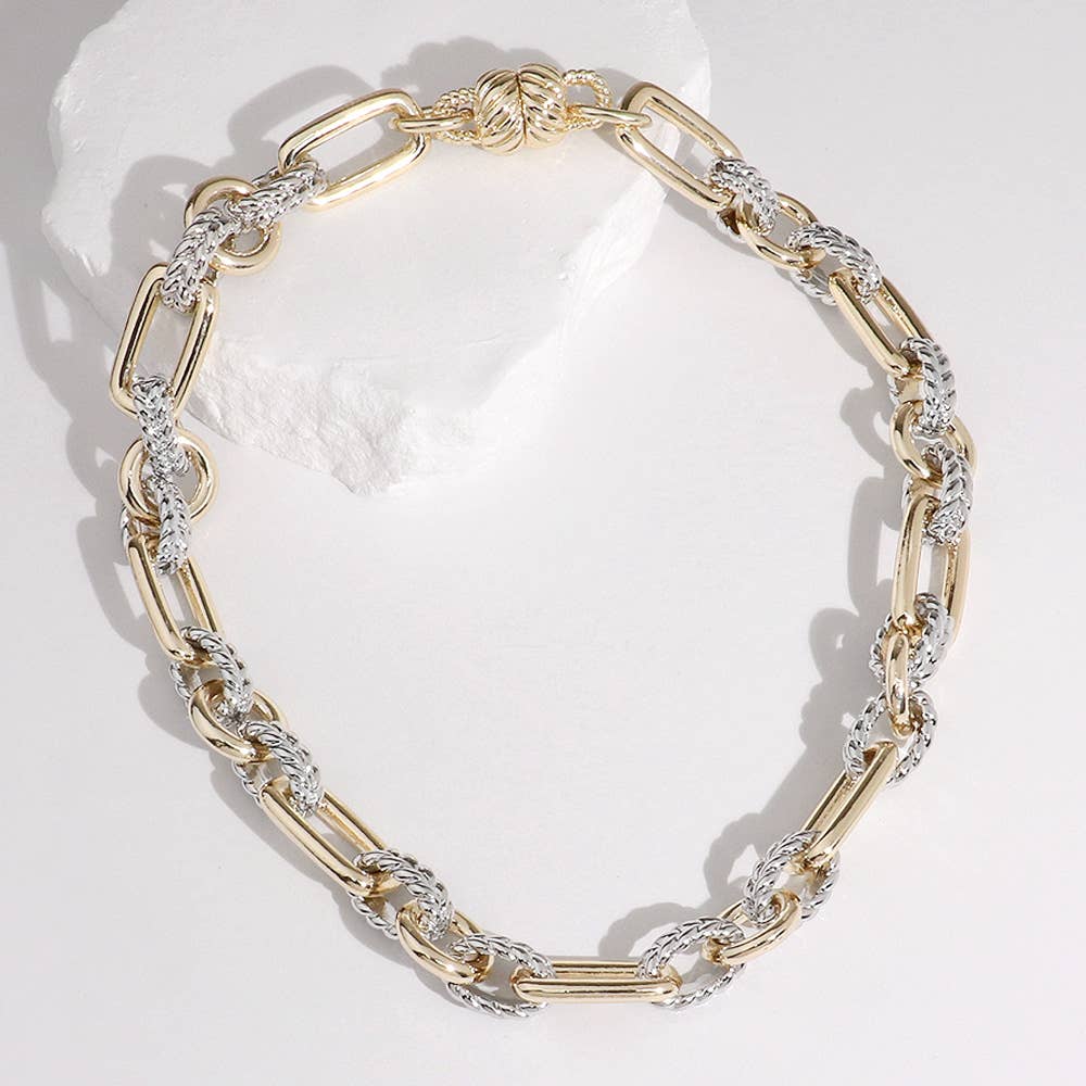Gold and silver link necklace on a white background.