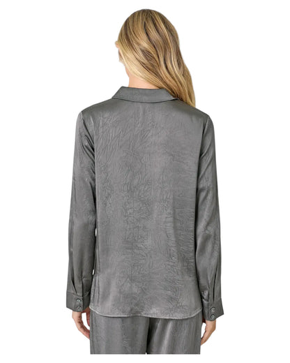 Woman wearing a grey button up crinkle satin twist front blouse. 
