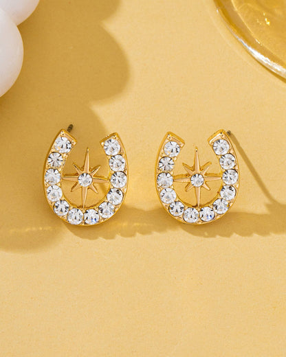 Gold horseshoe and star earrings with crystal accents on a yellow background.