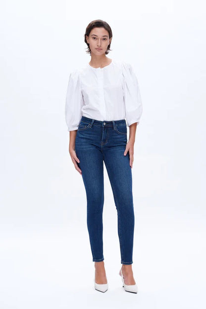 Model wearing dark blue mid-rise skinny jeans with a form-fitting silhouette and ankle-length cut.