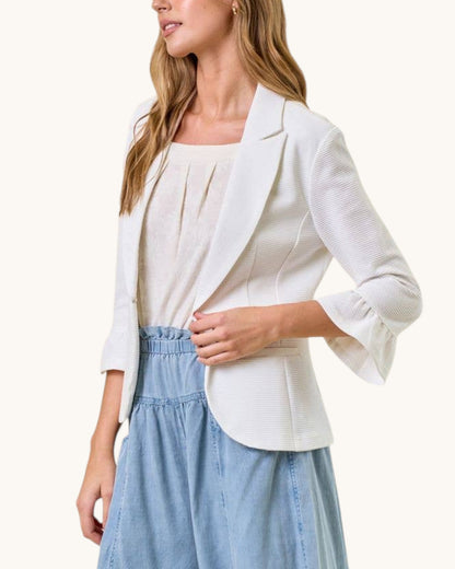 Woman wearing a white blazer over a light blue dress on a white background