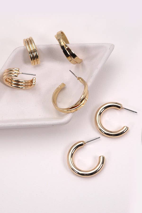 Gold hoop earrings on a white dish and surface.