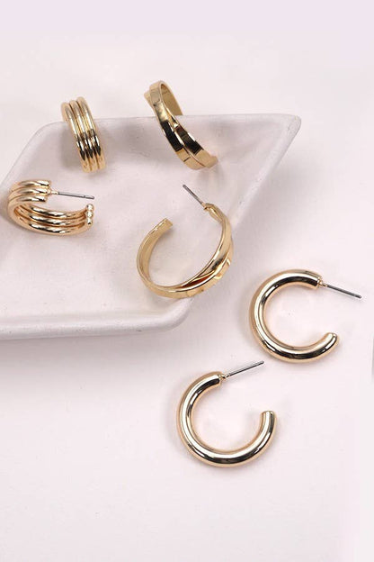 Gold hoop earrings on a white dish and surface.