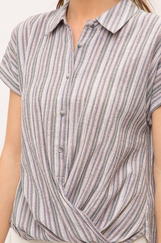 Woman wearing striped short sleeve button-up shirt with wrap front drape, collar and gold lurex detail.