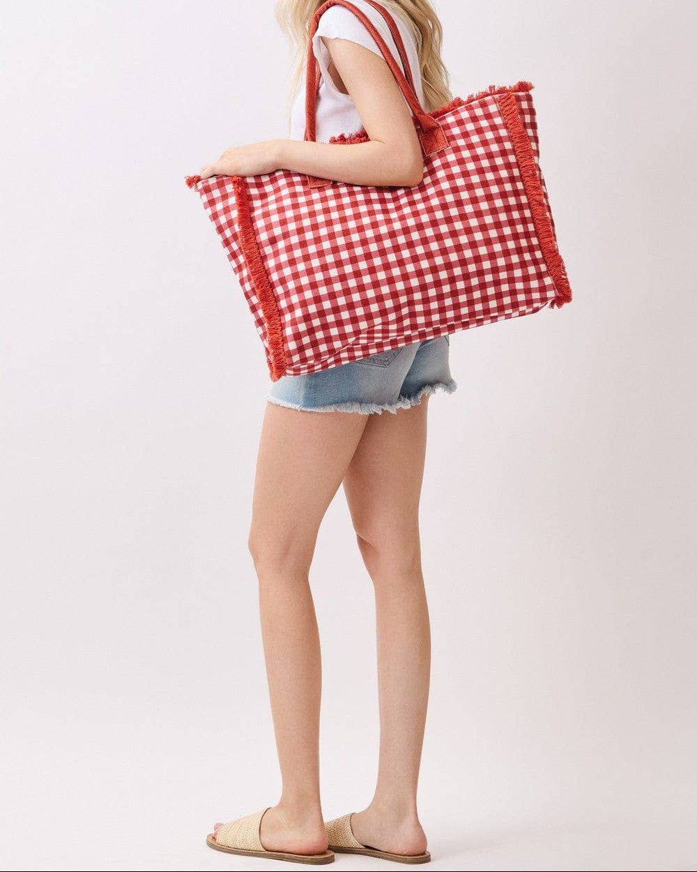 Woman holding a red and white checkered bag on a plain background