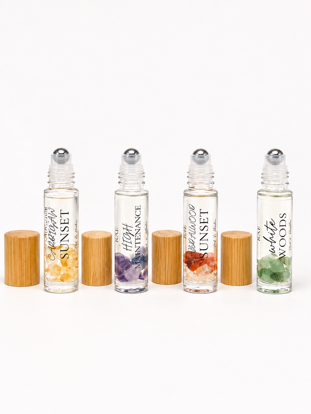 Set of four roller bottles with bamboo caps on a white background.