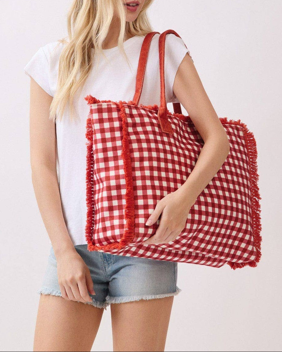 Woman holding a red and white checkered bag against a plain background.