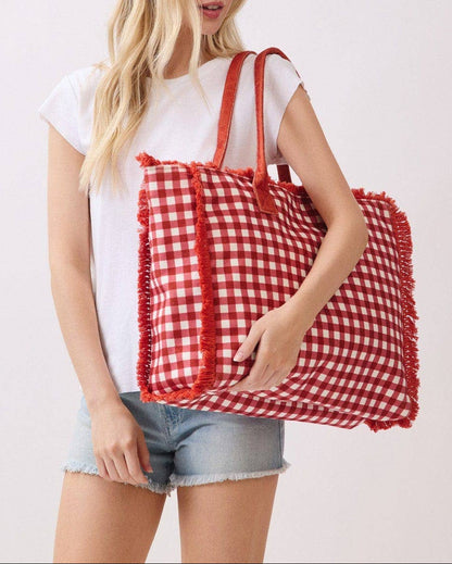 Woman holding a red and white checkered bag against a plain background.